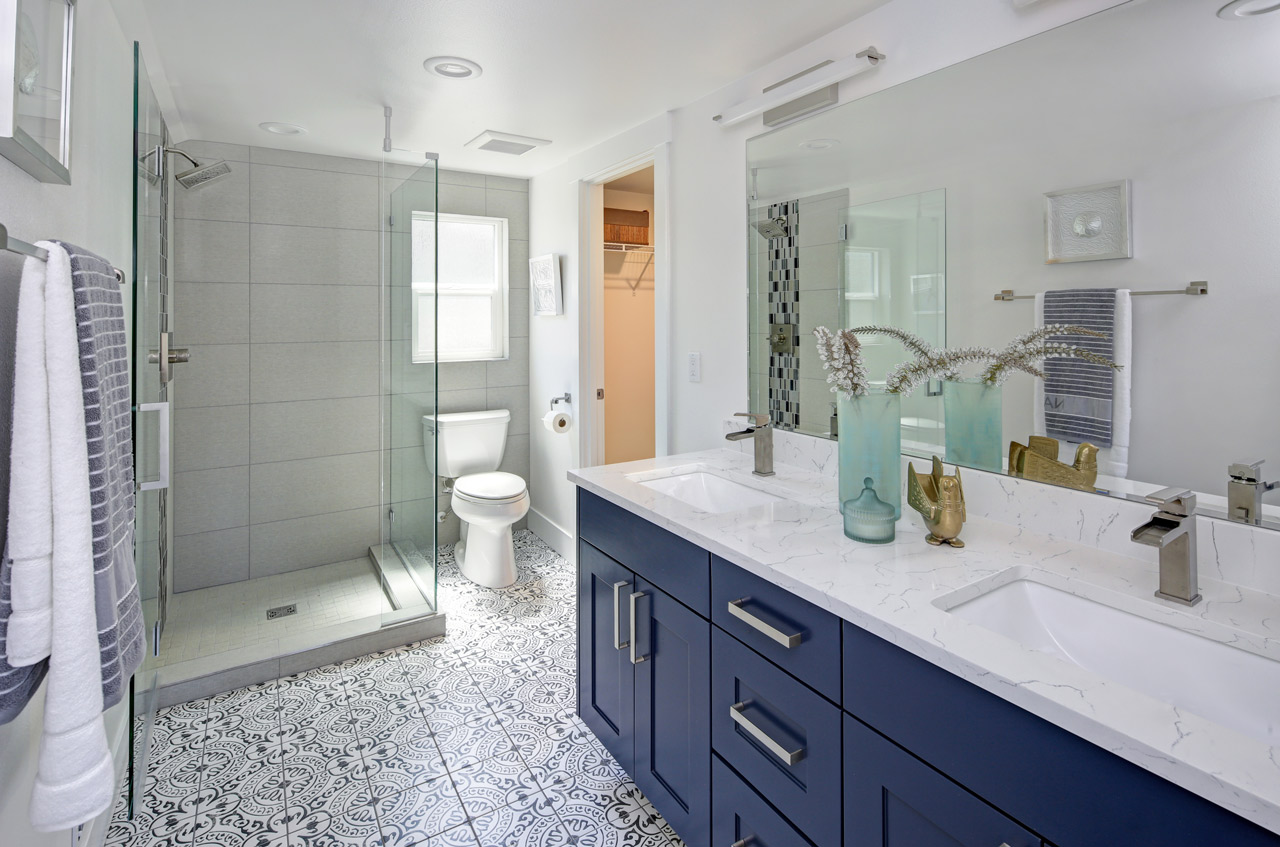 Remodeled bathroom with a glass shower, patterned tile floor and double vanity