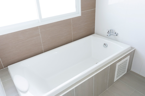 Refinished white bathtub against beige tiled wall — bathtub reglazing project by Magic of Tiles
