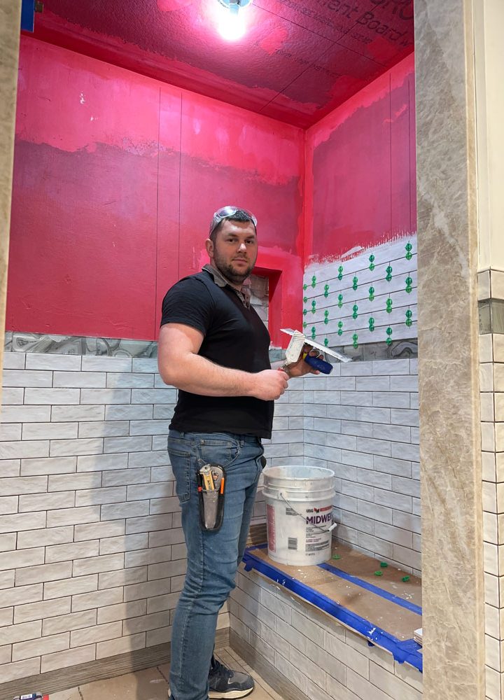 A tile installer using a trowel on an ongoing custom tile installation project