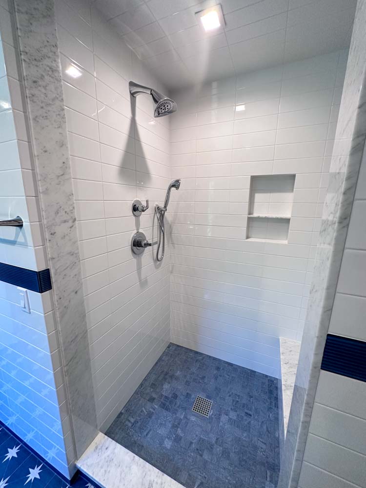 Simple porcelain tiled shower room wall with bath fixtures and niche