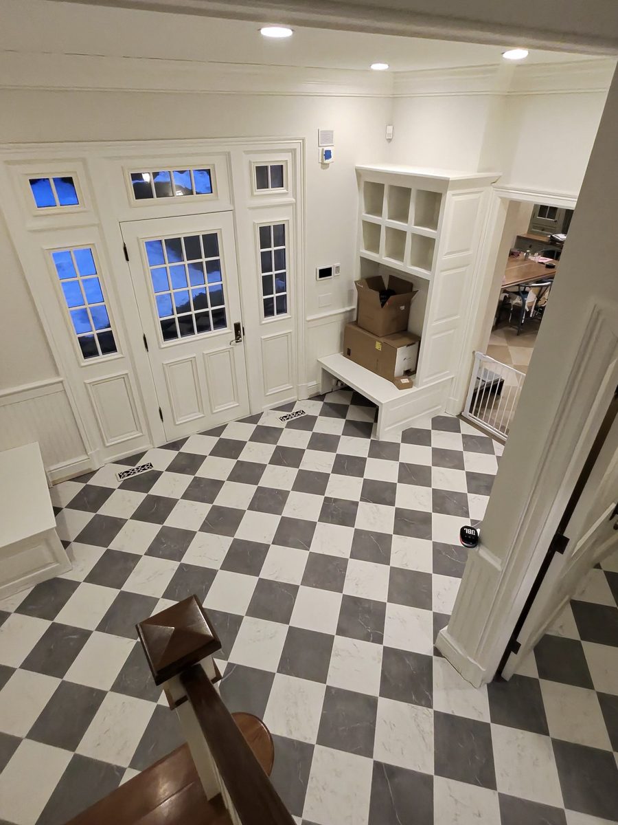 Grey and white checkerboard marble look tile floor in an entry and mudroom with a built in bench and cubby storage