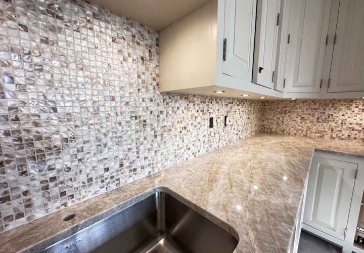 Stone and glass mosaic tiles kitchen backsplash, granite countertop, hanging cabinet with recessed under cabinet lighting